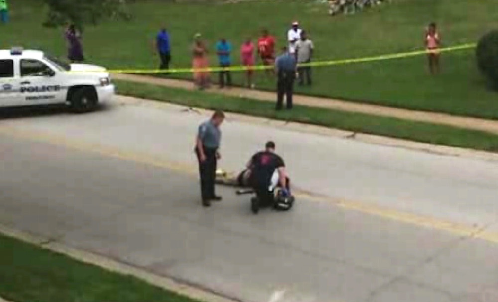 FILE - In this Saturday, Aug. 9, 2014 file image from TV provided by KMOV-TV, investigators inspect the body of Michael Brown, after he was shot, in Ferguson, Mo. Brown, who was fatally shot by police, suffered a bullet wound to his right arm that may have occurred when he put his hands up or when his back was turned to the shooter, "but we don't know," a pathologist hired by the teen's family said Monday, Aug. 18, 2014. (AP Photo/KMOV-TV, Tiffany Mitchell, File)