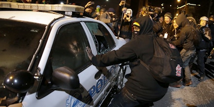 Protesters vandalize a police vehicle near Ferguson City Hall Tuesday, Nov. 25, 2014, in Ferguson, Mo. Missouri's governor ordered hundreds more state militia into Ferguson on Tuesday, after a night of protests and rioting over a grand jury's decision not to indict police officer Darren Wilson in the fatal shooting of Michael Brown, a case that has inflamed racial tensions in the U.S. (AP Photo/David Goldman)