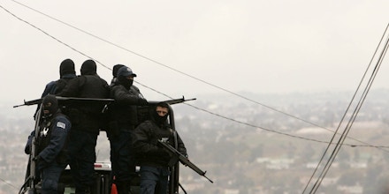 Armed police officials patrol a neighborhood in Tijuana, Mexico, Monday, Jan. 21, 2008. Mexican federal police found an underground shooting range and an arsenal of arms Saturday in this house in downtown Tijuana, which they say was a training ground for drug cartel hit men.  (AP Photo/Gregory Bull)