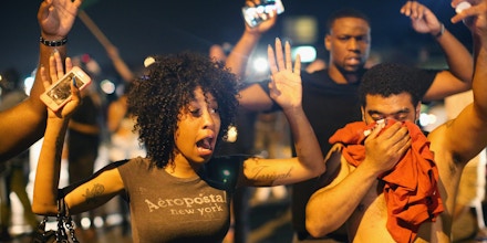 FERGUSON, MO - AUGUST 17:  Demonstrators protesting the killing of teenager Michael Brown by a Ferguson police officer try to stand their ground despite being overcome by tear gas on  August 17, 2014 in Ferguson, Missouri. Despite the Brown family's continued call for peaceful demonstrations, violent protests have erupted nearly every night in Ferguson since his death.  (Photo by Scott Olson/Getty Images)