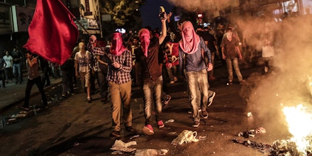 Left wing protesters shout slogans and hold red flag during a demonstration denouncing a police operation against Kurdish militants, on July 24, 2015 at Gazi district in Istanbul. Turkey on July 24 vowed to press on with operations against Islamic State (IS) in Syria and other militant groups, after its war planes bombed the jihadists' positions for the first time. Following the pre-dawn air raids on the IS targets in Syria, Turkish police arrested almost 300 suspected members of IS and pro-Kurdish militant groups nationwide, in one of Turkey's biggest recent crackdowns on extremists. AFP PHOTO/AFP PHOTO/YASIN AKGUL        (Photo credit should read YASIN AKGUL/AFP/Getty Images)