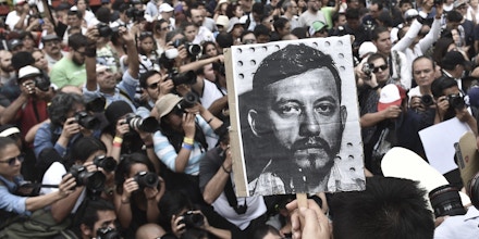 Mexican photojournalists hold pictures of their murdered colleague Ruben Espinosa during a demonstration held at the Angel of  Independence square in Mexico City, on August 2, 2015. Espinosa was found shot dead on August 1, 2015, in Mexico City, where he had moved two months ago from Veracruz, after reporting strong threats from the government of the state. Since 2010, 11 journalists have been killed and four others have gone missing in Veracruz. AFP PHOTO/ Yuri CORTEZ        (Photo credit should read YURI CORTEZ/AFP/Getty Images)