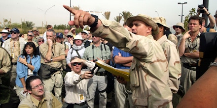 KUWAIT CITY - MARCH 11: Journalists listen to directions to their bus which will transport them to their embed site March 11, 2003 in Kuwait City. More than 600 journalists are being embedded in military units to cover a possible war with Iraq. (Photo by Joe Raedle/Getty Images)