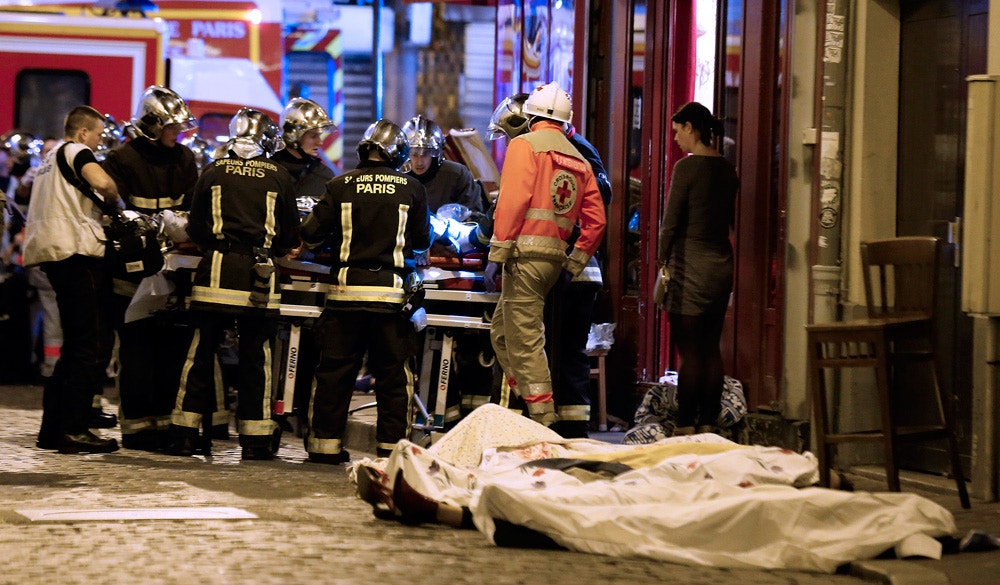 Rescue workers gather at victims in the 10th district of Paris, Friday, Nov. 13, 2015. Several dozen people were killed in a series of unprecedented attacks around Paris on Friday, French President Francois Hollande said, announcing that he was closing the country's borders and declaring a state of emergency. (AP Photo/Jacques Brinon)