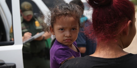MISSION, TX - JULY 24:  A mother and child, 3, from El Salvador await transport to a processing center for undocumented immigrants after they crossed the Rio Grande into the United States on July 24, 2014 in Mission, Texas. Tens of thousands of immigrant families and unaccompanied minors have crossed illegally into the United States this year and presented themselves to federal agents, causing a humanitarian crisis on the U.S.-Mexico border.  (Photo by John Moore/Getty Images)