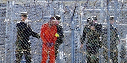 Guantanamo Bay, CUBA:  FOR USE WITH AFP STORIES: US-attacks-UN-Guantanamo (FILES) This 17 January, 2002, file photo shows a detainee (2nd L) wearing an orange jump suit surrounded by heavy security at the US Guantanamo Naval Base in Cuba. UN experts said on 16 February, 2006, the US must shut down the detention center without delay and release or try its inmates. The demand came in a report by five independent experts who act as monitors for the UN Human Rights Commission. The document charged that US treatment of the more than 500 