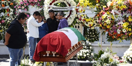 Family members of the slain mayor of Temixco, Gisela Mota, mourn next to her casket, during a ceremony in her honor, at the mayor's office building of Temixco, Mexico, Sunday, Jan. 3, 2016. Mota took office as mayor of the city of on Jan. 1 and was shot at her home on Jan. 2. The governor of the southern Mexican state of Morelos says the killing of the mayor was a warning by drug gangs, meant to convince other officials to reject state police control of local forces. (AP Photo/Tony Rivera)