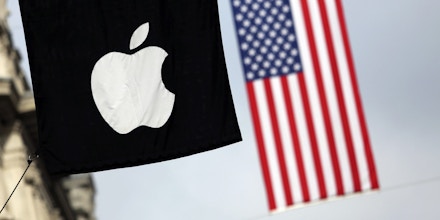 A U.S. flag flies beyond an Apple Inc. logo displayed outside the company's store on Regent Street in London, U.K., on Tuesday, Oct. 15, 2013. Burberry Group Plc named Christopher Bailey as chief executive officer to succeed Angela Ahrendts who will leave in 2014 to work as a senior vice president at Apple. Photographer: Chris Ratcliffe/Bloomberg via Getty Images