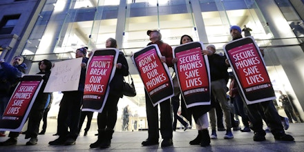 Protesters carry placards outside an Apple store Tuesday, Feb. 23, 2016, in Boston. Demonstrators are expected to gather in a number of cities Tuesday to protest the FBI obtaining a court order that requires Apple to make it easier to unlock an encrypted iPhone used by a gunman in December's shooting in San Bernardino, Calif. (AP Photo/Steven Senne)