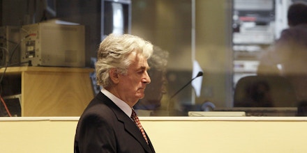 Former Bosnian Serb leader Radovan Karadzic, enters  the courtroom to enter pleas to 11 charges including genocide and crimes against humanity, at the U.N. Yugoslav war crimes tribunal in the Hague, Netherlands, Friday Aug. 29, 2008. Karadzic  refused to enter pleas to the 11 charges, including genocide and crimes against humanity, filed against him at the U.N.'s Yugoslav war crimes tribunal. After Karadzic's refusal to plead Friday, tribunal judge Iain Bonomy entered not guilty pleas on Karadzic's behalf. (AP Photo/ Valerie Kuypers, Pool)