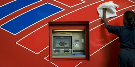 CHARLOTTE, NC - SEPTEMBER 15:  Queen Elizabeth Johnson, an employee of Redlee/SCS Group, cleans the front of an atm machine across the street from Bank of America's headquarters on September 15, 2008 in in Charlotte, North Carolina. After withdrawing from the competition to buy Lehman Brothers, Bank of America stepped in with an offer to buy Merrill Lynch for $50 billion. (Photo by Davis Turner/Getty Images)