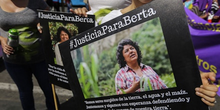 A woman holds a picture of Honduran Human Rights activist, Coordinator of the Civil Council of Popular and Indigenous Organizations of Honduras (COPINH) Berta Caceres Flores, reading 
