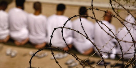 GUANTANAMO BAY, CUBA - OCTOBER 28: (EDITORS NOTE: Image has been reviewed by U.S. Military prior to transmission)  A group of detainees kneels during an early morning Islamic prayer in their camp at the U.S. military prison for 