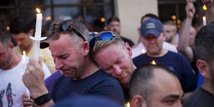 Paul Cox, right, leans on the shoulder of Brian Sullivan, as they observe a moment of silence during a vigil for a fatal shooting at an Orlando nightclub, Sunday, June 12, 2016, in Atlanta. (AP Photo/David Goldman)