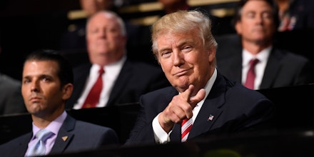 Donald Trump, 2016 Republican presidential nominee, right, gestures to delegates while sitting with son Donald Trump Jr. during the Republican National Convention (RNC) in Cleveland, Ohio, U.S., on Wednesday, July 20, 2016. Donald Trump, a real-estate developer, TV personality, and political novice, was formally nominated as the 2016 Republican presidential candidate Tuesday night in Cleveland after his campaign and party officials quashed the remnants of a movement to block his ascension. Photographer: David Paul Morris/Bloomberg via Getty Images