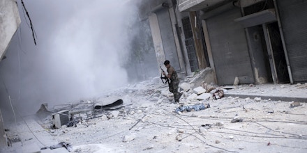In this Wednesday, Oct. 10, 2012 photo, a Free Syrian Army fighter looks for cover after firing his weapon against Syrian Army positions in the Karmal Jabl district in Aleppo, Syria. (AP Photo/ Manu Brabo)