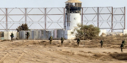 Israeli soldiers walk past a fence along Israel's border with the Gaza Strip, on August 4, 2014. An eight-year-old girl was killed and 30 people wounded in a strike on the beachfront Shati refugee camp in Gaza City just minutes into an Israeli-declared truce, medics said.  AFP PHOTO / JACK GUEZ        (Photo credit should read JACK GUEZ/AFP/Getty Images)