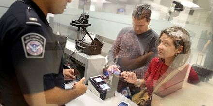 MIAMI, FL - MARCH 04: Leonel Cordova (L) and Noris Cordova speak to a CBP officer as they try to use their new mobile app at an entry point as the program is unveiled for international travelers arriving at Miami International Airport on March 4, 2015 in Miami, Florida. Miami-Dade Aviation Department and U.S. Customs and Border Protection (CBP) unveiled a new mobile app for expedited passport and customs screening. The app for iOS and Android devices allows U.S. citizens and some Canadian citizens to enter and submit their passport and customs declaration information using their smartphone or tablet and to help avoid the long waits in the exit lanes. (Photo by Joe Raedle/Getty Images)
