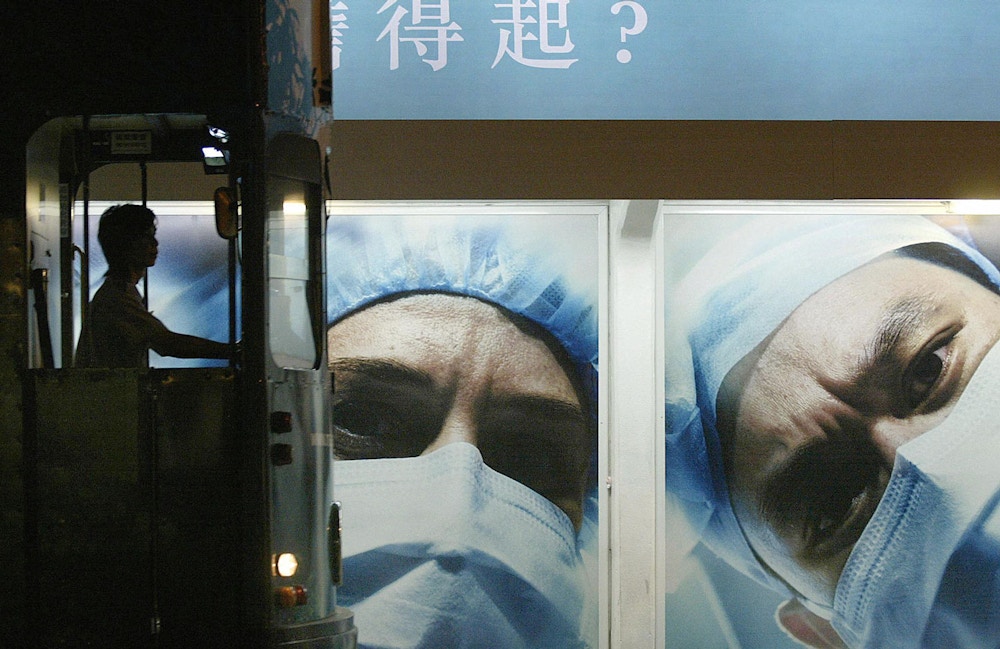 HONG KONG, CHINA:  A tram driver is silhouetted at a tram stop in front of a billboard showing medical workers doctor wearing masks to prevent the SARS disease in the Central district of Hong Kong, 07 May 2004.  Although China's first 2004 SARS patient, a lab worker in Beijing, will be discharged from hospital 10 May 2004 and only one person on the mainland has died so far, authorities in Hong Kong have continued to push public service advertisements warning local citizens to be diligent in the fight against the disease which caused almost 800 deaths in 2003, nearly 300 in the former British colony.    AFP PHOTO/Samantha SIN  (Photo credit should read SAMANTHA SIN/AFP/Getty Images)