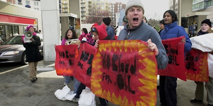 WASHINGTON, :  Activists stage a protest 04 December, 2002 at an Exxon gas station in Washington, DC to highlight the role of the oil industry in pushing for a US invasion of Iraq. The demonstrators, chanting 