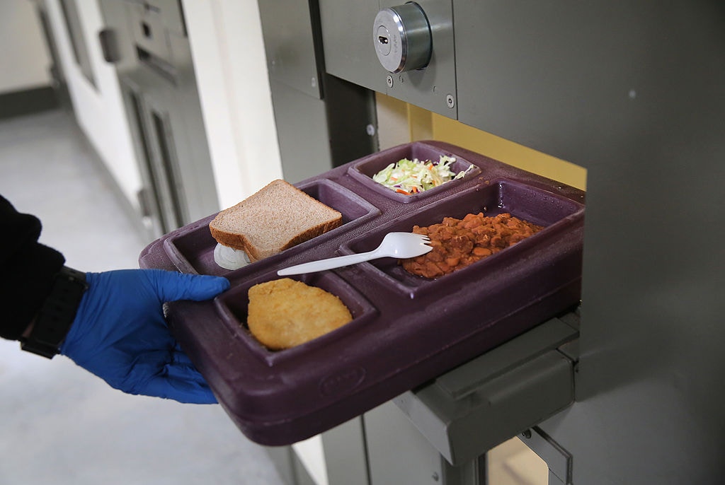 ADELANTO, CA - NOVEMBER 15: A guard serves lunch to an immigrant detainee in his 'segregation cell' during lunchtime at the Adelanto Detention Facility on November 15, 2013 in Adelanto, California. Most detainees in segregation cells are sent there for fighting with other immigrants, according to guards. The facility, the largest and newest Immigration and Customs Enforcement (ICE), detention center in California, houses an average of 1,100 immigrants in custody pending a decision in their immigration cases or awaiting deportation. The average stay for a detainee is 29 days. The facility is managed by the private GEO Group. ICE detains an average of 33,000 undocumented immigrants in more than 400 facilities nationwide. (Photo by John Moore/Getty Images)