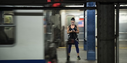 NEW YORK, NY - JULY 20: A woman looks at her smartphone as a train passes by at the 14th Street subway station, July 20, 2016 in New York City. The Metropolitan Transportation Authority (MTA) has placed digital signage in subway stations encouraging riders to be safe while playing the Pokemon Go app on their smartphones. (Photo by Drew Angerer/Getty Images)