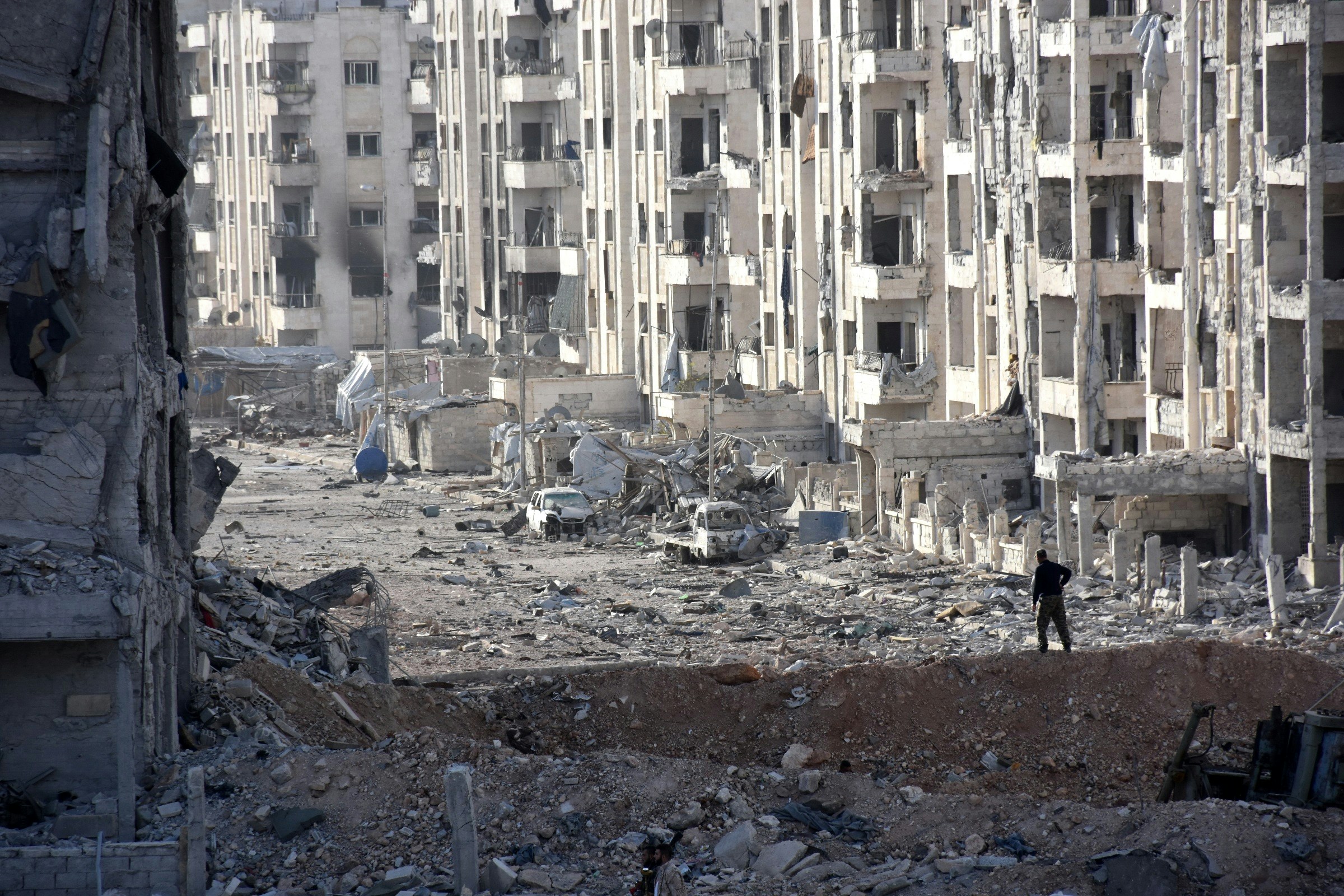 TOPSHOT - A member of the Syrian pro-government forces stands amid heavily damaged buildings in Aleppo's 1070 district on November 8, 2016, after troops seized it from rebel fighters. Syrian state media said government forces had advanced southwest of divided second city Aleppo, seizing the 1070 district from rebel forces. The Syrian Observatory for Human Rights monitor also reported the advance, saying it would allow government forces to protect areas already under their control on the southern outskirts of Aleppo.  / AFP / GEORGES OURFALIAN        (Photo credit should read GEORGES OURFALIAN/AFP/Getty Images)