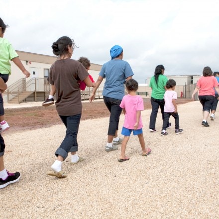 DILLEY, TEXAS - May 14, 2015: Residents walk through the facility grounds to eat lunch at the cafeteria. The South Texas Family Residential Center in Dilley, Texas was built in December 2014 to host up to 2,400 undocumented women and children who are seeking asylum. The Dilley facility is the largest of its kind, and while residents may move freely from building to building, they are not permitted to leave the grounds.