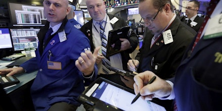 Specialist Mark Fitzgerald, left, works with traders at his post on the floor of the New York Stock Exchange, Tuesday, Jan. 10, 2017. The stock market is getting off to a mixed start as drops in real estate and utilities offset gains in other sectors including health care. (AP Photo/Richard Drew)