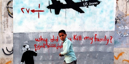 A Yemeni boy (C) walks past a mural depicting a US drone and reading 