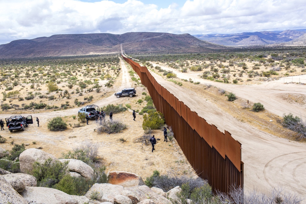 TIJUANA, MX. - APRIL 8 2016: Mexican Federal Policeman escort a tour of the border wall near Tijuana. Natalie Keyssar