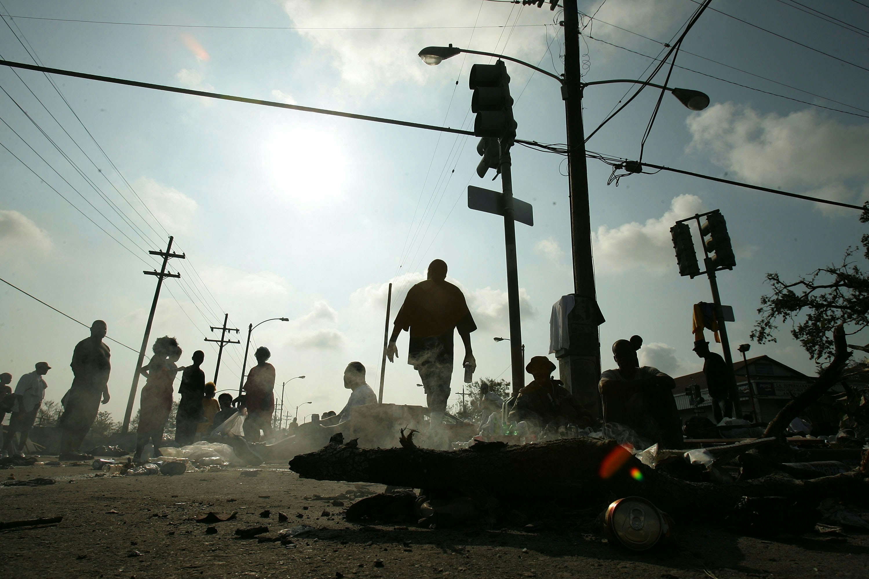 NEW ORLEANS - AUGUST 31:  People wait for assistance after being rescued from their homes a day earlier in the Ninth Ward as a small fire burns after Hurricane Katrina August 31, 2005 in New Orleans, Louisiana. Devastation is widespread throughout the city with water approximately 12 feet high in some areas. Hundreds are feared dead and thousands were left homeless in Louisiana, Mississippi, Alabama and Florida by the storm.  (Photo by Mario Tama/Getty Images)