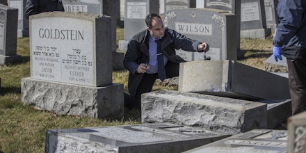 Northeast Philadelphia Police Detective Timothy McIntyre, center, dusts for fingerprints on one of the headstones that were vandalized at Mount Carmel Cemetery in Philadelphia on Sunday, Feb. 26, 2017. More than 100 headstones have been vandalized at the Jewish cemetery in Philadelphia, damage discovered less than a week after similar vandalism in Missouri, authorities said. (Michael Bryant/The Philadelphia Inquirer via AP)