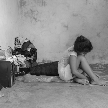 A 10-year-old migrant fleeing gang threats in El Salvador sits on the blankets her family uses in the absence of a bed in their rented home in Tapachula, Chiapas. The family applied for refugee status but were denied, so they don't have working papers. They hope to continue traveling to the U.S.