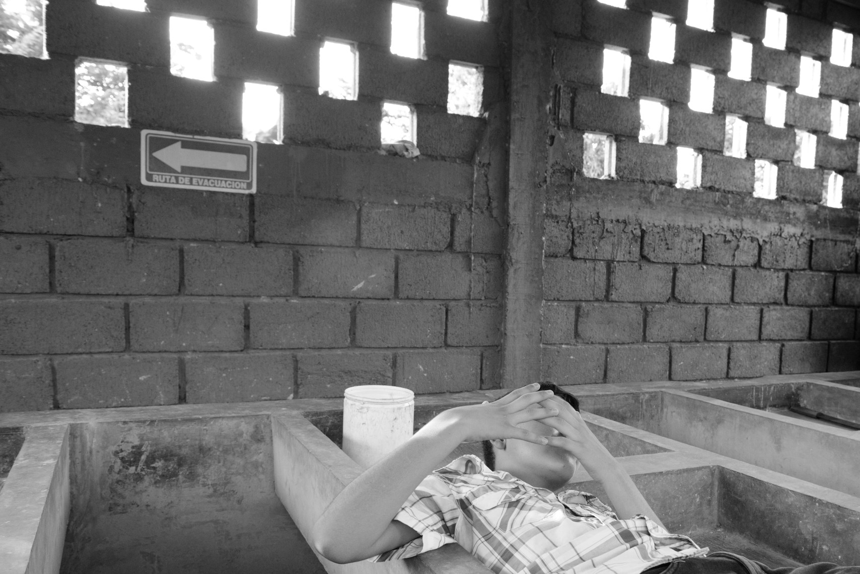A 13-year-old Honduran boy reclines in a sink for washing clothes at a refuge for families seeking asylum in Tapachula, Chiapas. Gang members killed his father, a police officer, six years ago. They demanded his mother hand over half of the money she earned selling food on the street, then later insisted the boy join the gang or his 15-year-old sister become their girlfriend, so the family fled.They now live in a shelter for asylum-seekers as their application for refugee status is processed. They're grateful for the refuge, but the donated food is often scarce and they are allowed to leave just once a day and must be back by 6:00PM. They are terrified that gang members will spot them, as the city is full of migrants from Honduras.