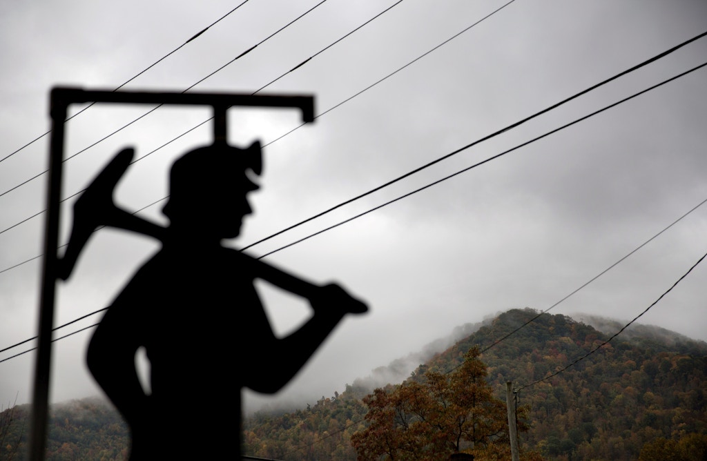 In this Oct. 16, 2014 photo, fog hovers over a mountaintop as a cut out of a coal miner stands at a memorial to local miners killed on the job in Cumberland, Ky. For over a century, life in Central Appalachia has been largely defined by the ups and downs of the coal industry. Through all the bust years, there was always the promise of another boom. Until now. There is a growing sense in these mountains that this downturn is different, deeper. That for a variety of reasons, economic, environmental, political, coal mining will not rebound this time. As recently as the late 1970s, there were more than 350 mines operating at any given time in Harlan County. Today, it's around 40. (AP Photo/David Goldman)