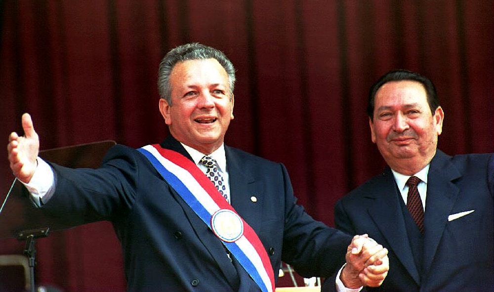 ASUNCION, PARAGUAY - AUGUST 15:  Paraguayan newly-sworn in President Juan Carlos Wasmosy (L) acknowledges the applause 15 August 1993 after receiving the presidential sash from his predecessor Andres Rodriguez (R) during the inauguration ceremony. Wasmosy, a 54-year-old businessman of Hungarian descent, becomes Paraguay's first democratically-elected civilian president in half a century.  (Photo credit should read NORBERTO DUARTE/AFP/Getty Images)