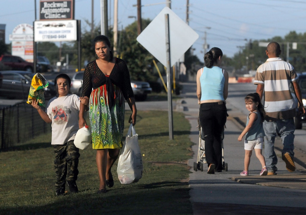 In this photo taken Thursday Sept. 30, 2011, undocumented immigrants from Mexico, Fredy and Anahi Martinez, right, walk with their two children to the supermarket in Norcross, Ga. The couple has been in the United States for the past 12 years and say they would risk deportation if they drove a car without a driver’s license because of the enforcement of the 287(g) program in their community, which allows state and local law enforcement agencies to question anyone on their immigration status for any infraction of the law such as driving without a license. (AP Photo/Erik S. Lesser)
