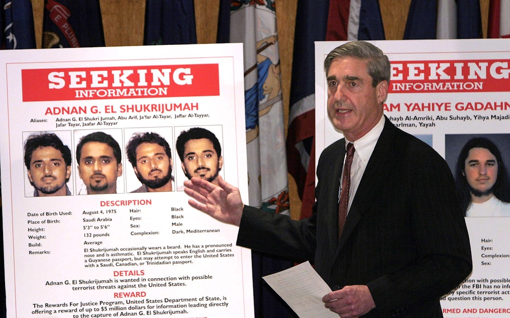 UNITED STATES - MAY 26:  FBI Director Robert S. Mueller III gestures toward a placard bearing photos of suspected terrorist Adnan G. El Shukrijumah at a news conference in Washington, DC on Wednesday, May 26, 2004. The U.S. has "credible intelligence from multiple sources" that al-Qaeda plans to attack the U.S. in the next few months, Attorney General John Ashcroft said.  (Photo by Dennis Brack/Bloomberg via Getty Images)