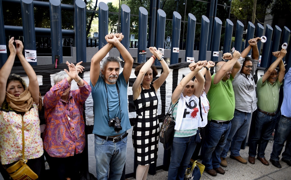 Civil society activists and journalists pretend to turn themselves in during a protest against alleged government spying on the media and human rights defenders, outside the attorney general's office in Mexico City on June 23, 2017. Mexican prosecutors said Wednesday they have opened an investigation into allegations the government spied on leading journalists, human rights activists and anti-corruption campaigners. / AFP PHOTO / ALFREDO ESTRELLA (Photo credit should read ALFREDO ESTRELLA/AFP/Getty Images)