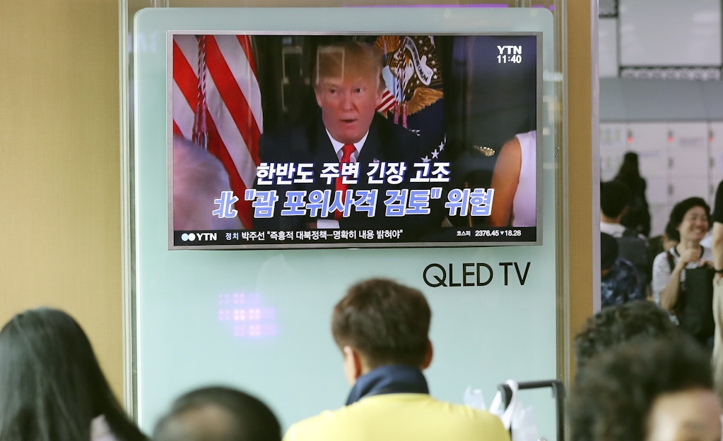 People watch a TV screen showing a local news program with an image of U.S. President Donald Trump, at Seoul Train Station in Seoul, South Korea, Wednesday, Aug. 9, 2017. North Korea and the United States traded escalating threats, with President Donald Trump threatening Pyongyang "with fire and fury like the world has never seen" and the North's military claiming Wednesday it was examining its plans for attacking Guam. The letters read "North Korea, Examine, the enveloping fire at Guam." (AP Photo/Lee Jin-man)