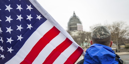 A pro-Israel demonstrator, wearing a military style kipa and holding an American flag, attends a demonstration outside the U.S. Capitol, while Israeli Prime Minister Benjamin Netanyahu addresses a joint session of Congress. (Photo by Brooks Kraft LLC/Corbis via Getty Images)