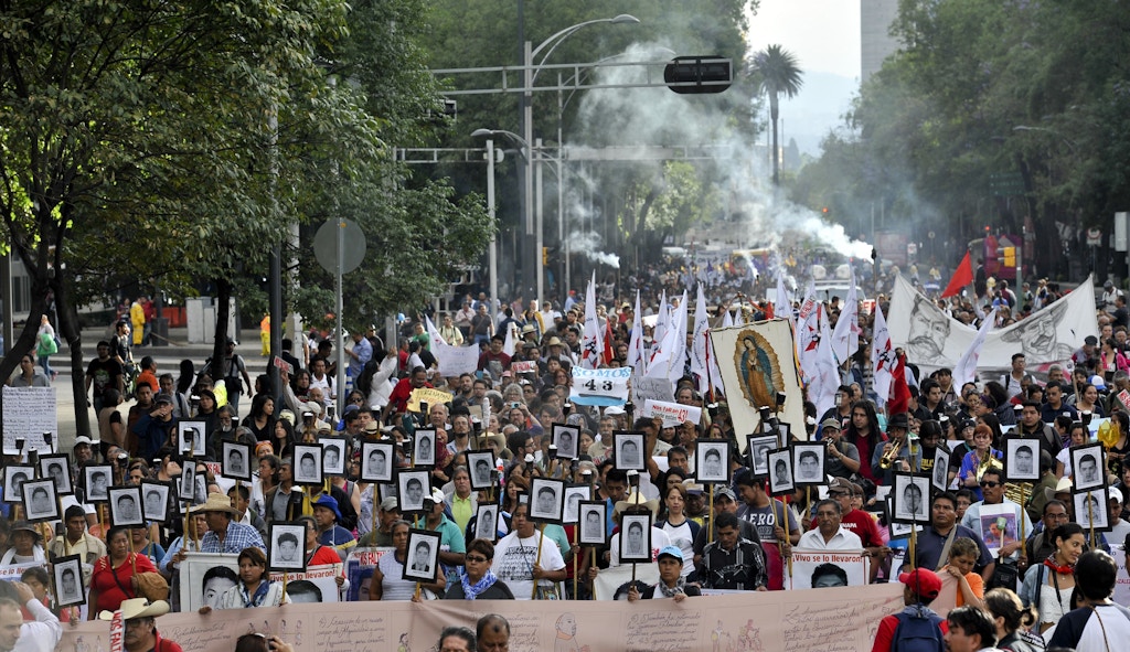 The parents of 43 missing students from Ayotzinapa teachers school hold their portraits and torches during a march 18 months after their disappearance in Mexico City on April 26, 2016. / AFP / YURI CORTEZ        (Photo credit should read YURI CORTEZ/AFP/Getty Images)