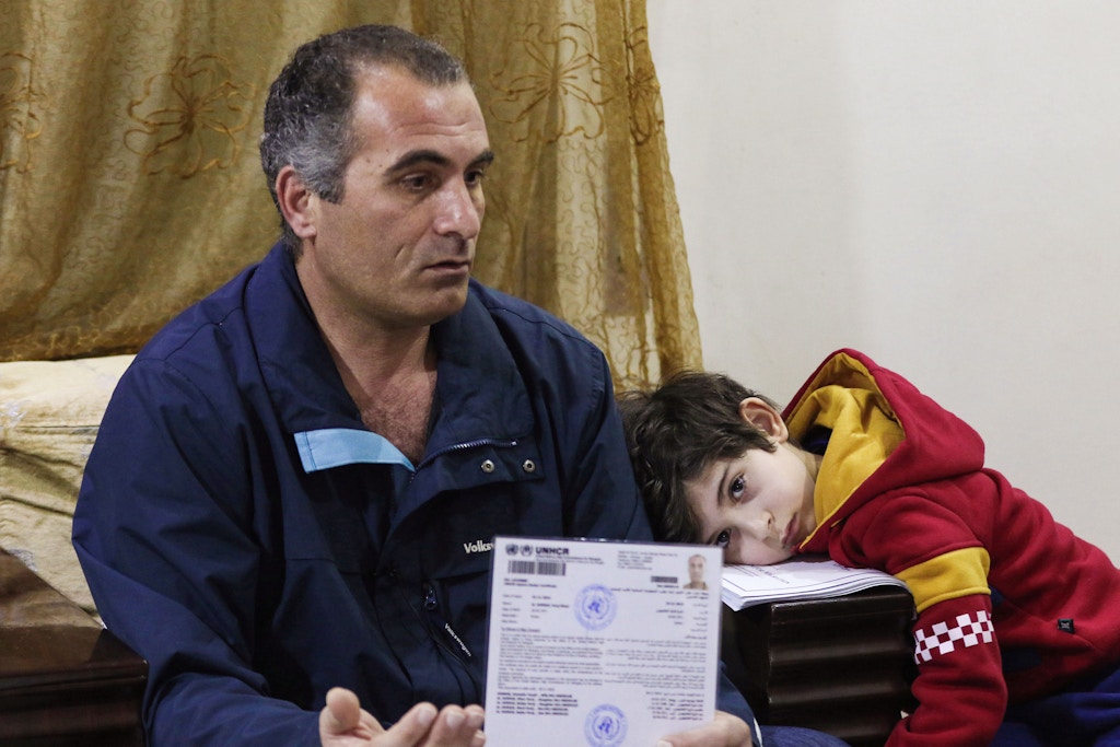 Faraj Ghazi al-Jamous, a Syrian refugee who was prevented from travel to the United States due to President Donald Trump's executive order blocking entry to citizens from seven Muslim-majority countries, including Syria, sits in a living room with his son, showing documents provided by the UNHCR verifying his status, in the Jordanian capital Amman on February 1, 2017. After spending over a year amid interviews, health and security checks, Jamous, a father of five who was travelling with his wife and children, was contacted by a representative from the International Organisation of Migration (IOM) who told him that the family's immigration and resettlement plans were suspended indefinitely. / AFP / Khalil MAZRAAWI        (Photo credit should read KHALIL MAZRAAWI/AFP/Getty Images)