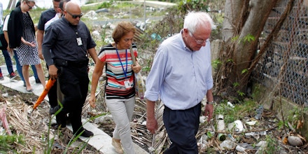 US Sen. Bernie Sanders (I- VT) walks over debris caused by the passing of Hurricane Maria through the area during a visit with the Mayor of San Juan Carmen Yulin to the Playita community in San Juan, Puerto Rico, on October 27, 2017.More than 73,000 people have fled emergency conditions at home for Florida since Hurricane Maria devastated the US territory in the Caribbean. / AFP PHOTO / Ricardo ARDUENGO (Photo credit should read RICARDO ARDUENGO/AFP/Getty Images)