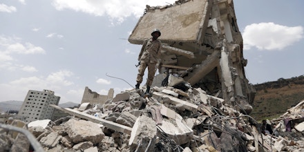 TOPSHOT - A Yemeni soldier stands on the debris of a house, hit in an air strike on a residential district, in the capital Sanaa on August 26, 2017.Children were among at least 14 people killed in an air strike that toppled residential blocks in Yemen's capital Sanaa on Friday, witnesses and medics said. / AFP PHOTO / MOHAMMED HUWAIS (Photo credit should read MOHAMMED HUWAIS/AFP/Getty Images)