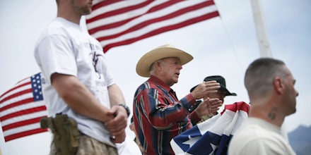 FILE - In this April 18, 2014, file photo, flanked by armed supporters, rancher Cliven Bundy speaks at a protest camp near Bunkerville, Nev. A U.S. judge has set a Jan. 8, 2018, date to decide whether charges should be dismissed outright in the prosecution of Cliven Bundy, sons Ryan and Ammon Bundy, and Montana militia leader Ryan Payne. They're charged with organizing and leading an armed uprising against federal agents to stop a roundup of Bundy cattle near the Nevada town of Bunkerville in April 2014. (John Locker /Las Vegas Review-Journal via AP, File)