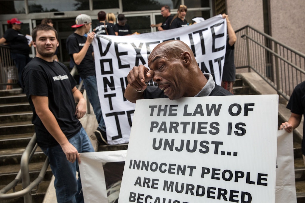 Mark Clements (R), who was imprisoned for 28 years before being released and exonerated, wipes sweat from his brow while advocating for the commutation of Jeff Wood's sentence outside of the Texas State Insurance Building, where the Office of Governor Gregg Abbott is located, on August 18, 2016 in Austin, Texas. Clements joined friends and family of Jeff Wood and anti-death penalty activists to deliver a petition with over 10,000 signatures asking the governor and the Texas Board of Pardons and Paroles to commute Wood's sentence. Jeff Wood is scheduled to be executed by the state of Texas on August 24, 2016 under what is referred to as the "law of parties" for a criminal act he committed on January 2, 1996. The Texas law says that if a person, " acting with intent to promote or assist the commission of the offense, he solicits, encourages, directs, aids, or attempts to aid the other person to commit the offense;" then they are criminally responsible for the conduct of another, as well. / AFP / TAMIR KALIFA (Photo credit should read TAMIR KALIFA/AFP/Getty Images)