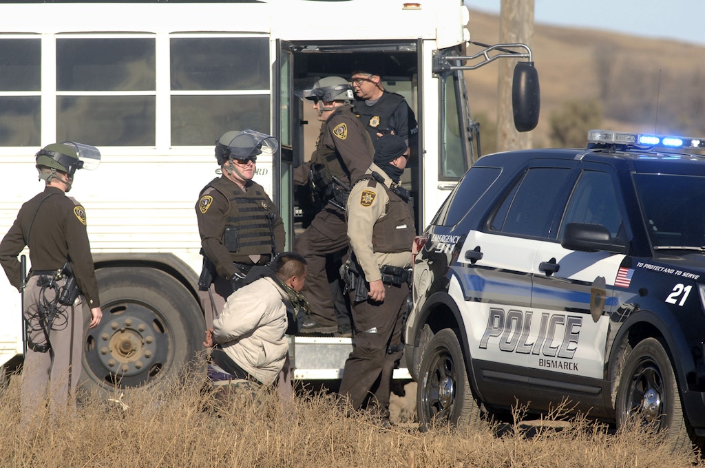 A Dakota Access Pipeline protester is arrested and waiting transportation to the Morton County jail on Tuesday, Nov. 15, 2016, after a large gathering of protesters tried to block a railroad crossing on Old Highway 10 and County Road 82 west of Mandan, N.D. (Mike McCleary /The Bismarck Tribune via AP)