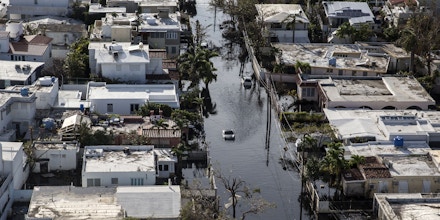Bloomberg Best of the Year 2017: A vehicle drives through streets filled with floodwater and past destroyed homes caused by Hurricane Maria in this aerial photograph taken above Barrio Obrero in San Juan, Puerto Rico, on Monday, Sept. 25, 2017. Photographer: Alex Wroblewski/Bloomberg via Getty Images